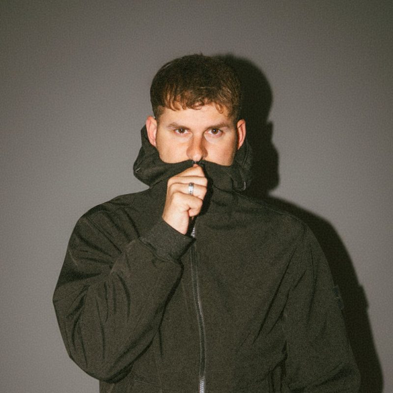 RSCL, el DJ y productor neerlandés Franklin van Beek, con una sudadera verde oscuro hasta la boca ante una pared gris