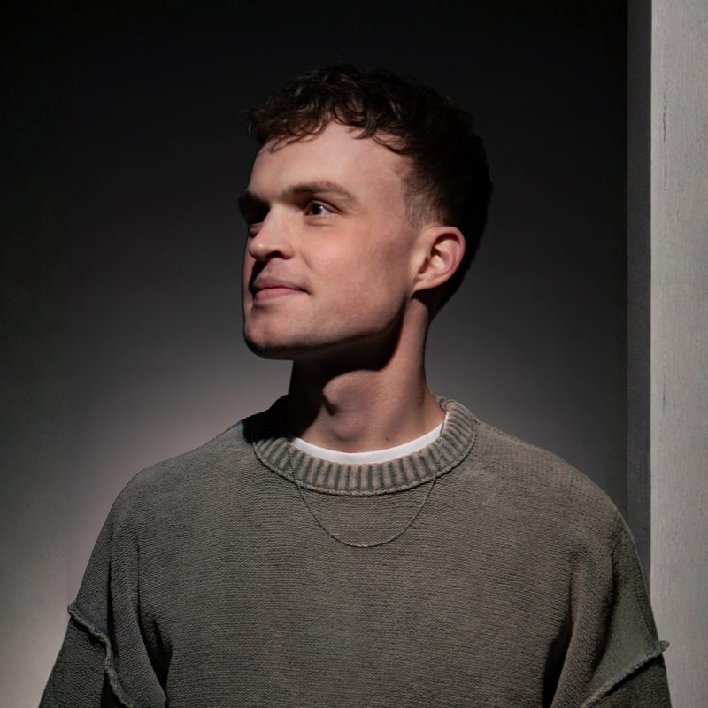 S3PPA, niederländischer Hard-House- und Trance-DJ, im grauen Strickpulli mit Kette, seitlicher Blick